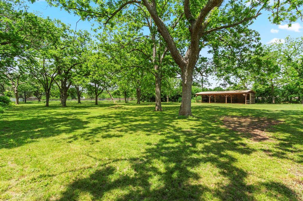 Back pasture view with open air barn. Lots of mature trees throughout the property. This area is cross fenced.