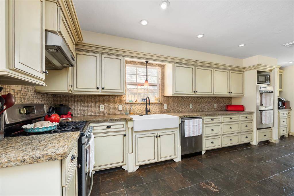 This impressive Kitchen has ample counter space, beautiful custom cabinets, a large farm sink, double ovens, gas range, and massive pantry!