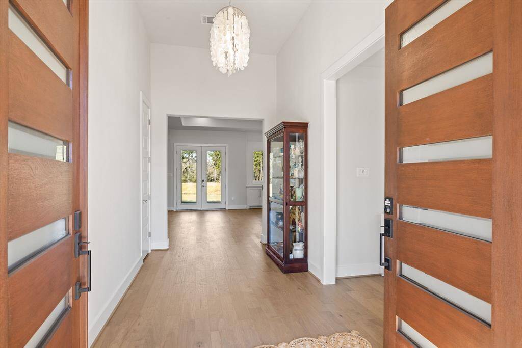 Stunning 8-foot mahogany stained, weather resistant double doors make a grand statement. Richly hued with soft, warm tones, the combination of glass & wood tones adds a touch of luxury & elegance, setting the vibe for the entire home. The sleek, contemporary design of the doors, with their clean lines & refined hardware, invites guests in with an air of sophistication and warmth. This beautiful entrance serves as the perfect first impression, effortlessly blending modern style with timeless craftsmamship.
