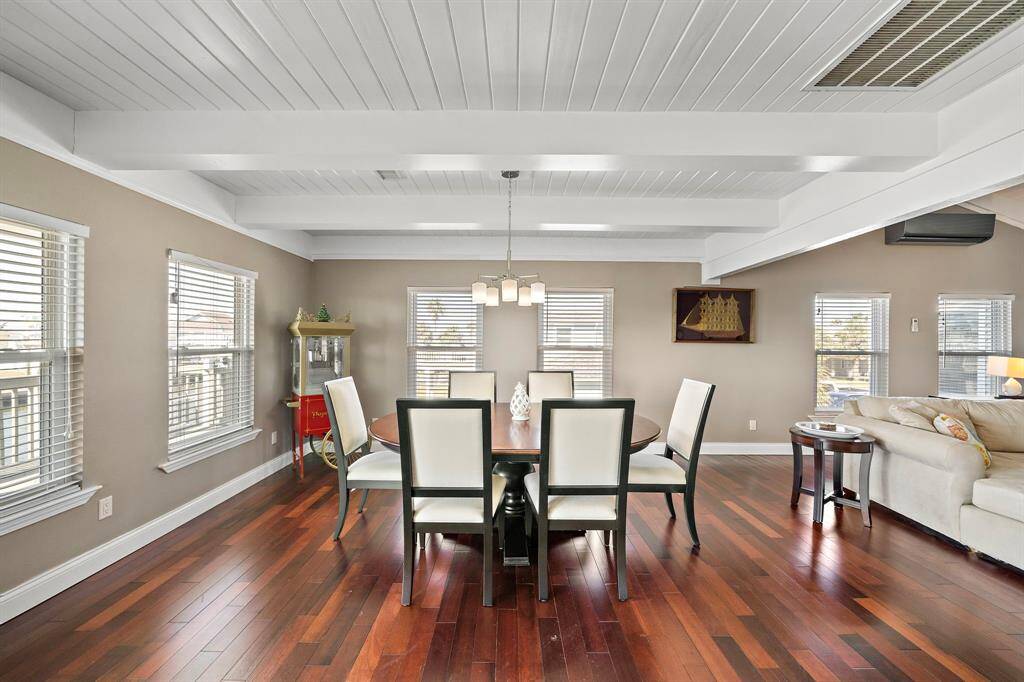 A generous dining space with crisp white ceilings and hardwood flooring, comfortably fitting a large dining set. Surrounded by windows, this area brings in ample sunlight and offers tranquil views—ideal for gatherings and memorable meals with friends and family.