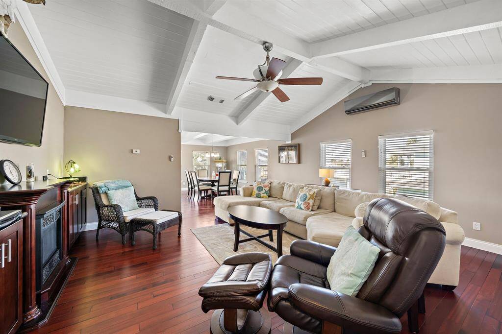 This view showcases the spaciousness of the living room, complete with a plush sectional and recliners. The open sightlines to the dining area and kitchen enhance the airy, inclusive feel of the layout.