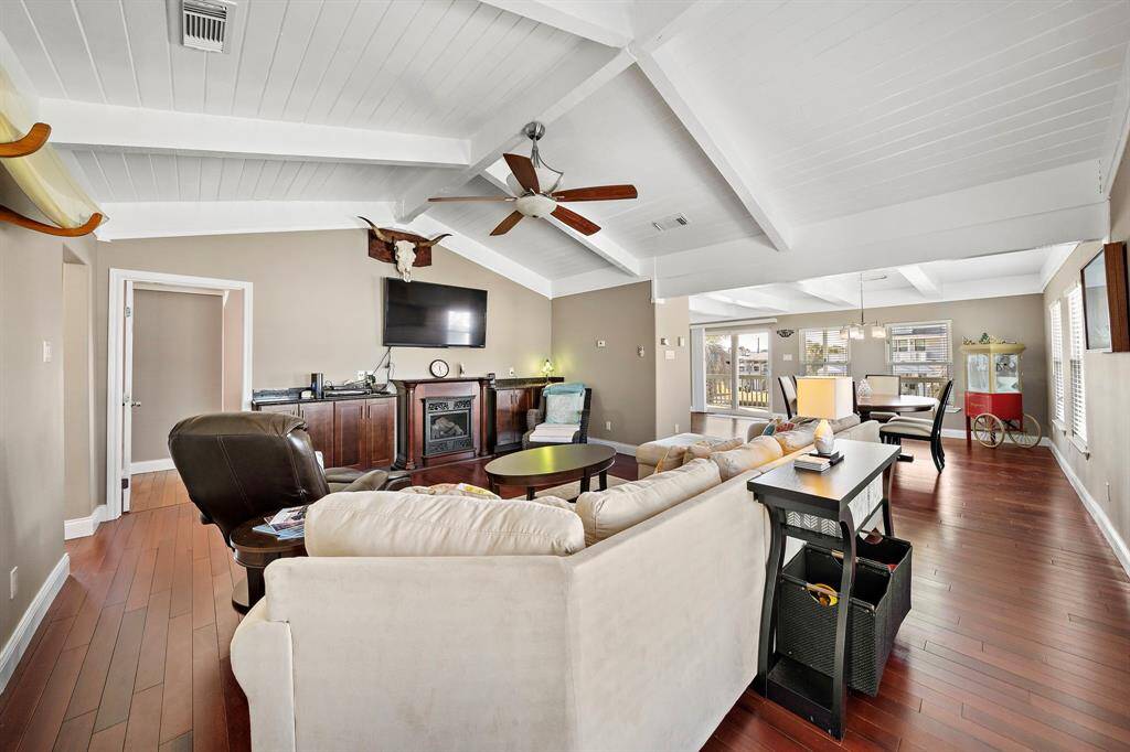 From this angle, you can appreciate the vaulted white ceilings and exposed beams that define the home’s coastal character. The living space flows effortlessly into the dining and kitchen areas, creating a true open-concept layout that’s perfect for entertaining.