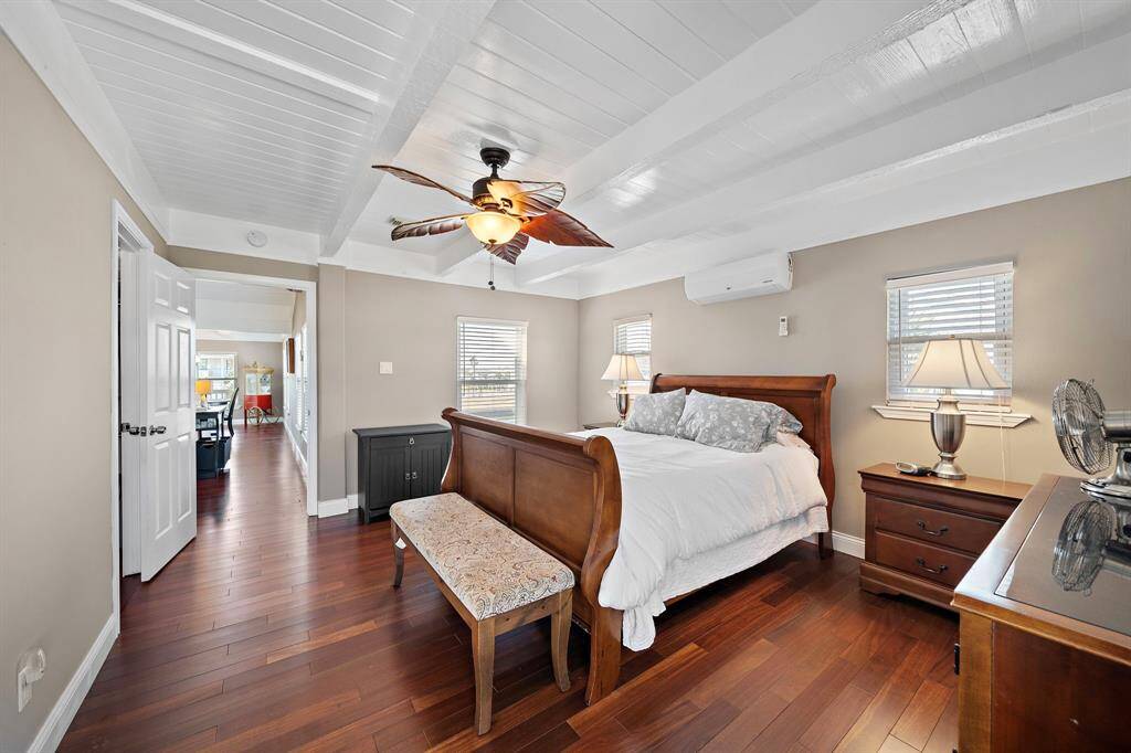 This view of the primary suite shows the flow into the main living area, with natural light streaming through multiple windows. The classic sleigh bed and tasteful furnishings create a restful, elegant retreat.