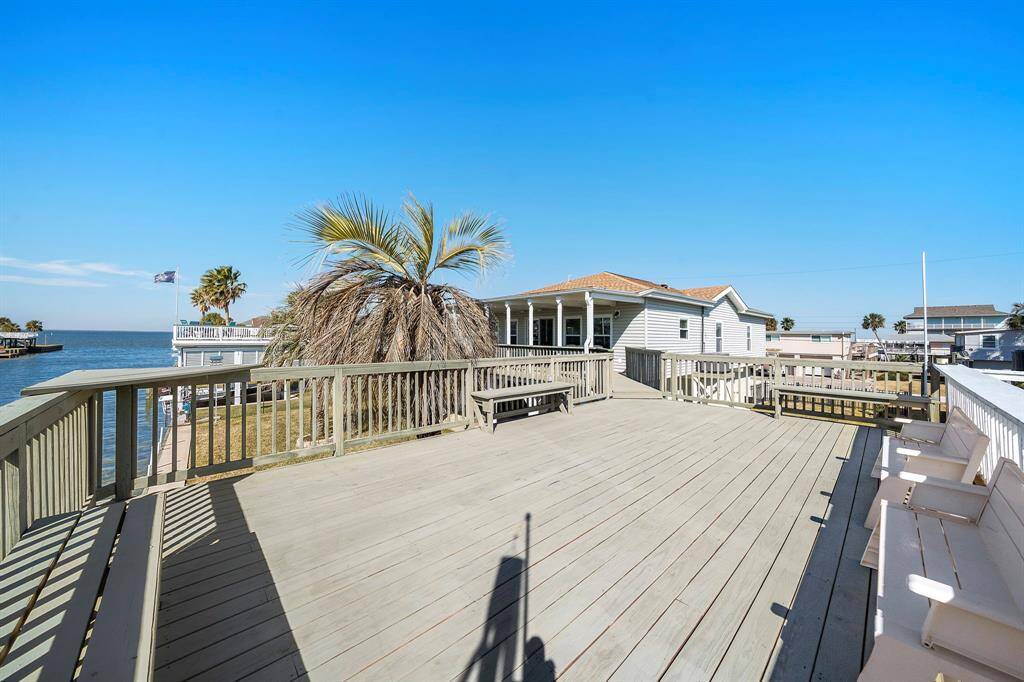 A wide deck on the upper boat dock level, with seating benches and plenty of room for entertaining. This vantage point shows the home, canal, and even open waters in the distance.