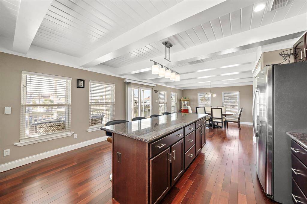 An open-concept kitchen and dining space ideal for entertaining. Featuring a long center island, bar seating, stainless steel appliances, and ample windows for a light, airy feel. Flows directly to the outdoor deck for easy indoor-outdoor living.