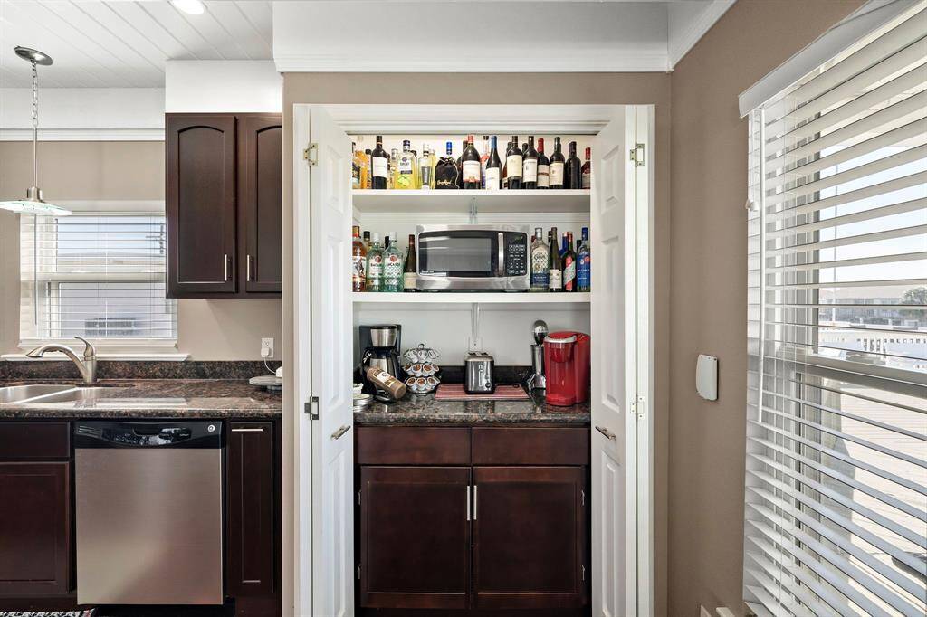 Tucked behind double doors, this cleverly designed pantry doubles as a beverage bar—complete with wine storage, a microwave, coffee makers, and open shelving. Ideal for entertaining and morning routines alike.