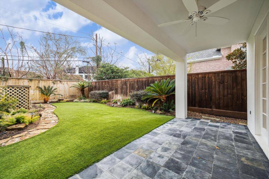 Covered backyard porch with an overhead fan. The slate patio offers a shady spot to converse and entertain. The recent turfed yard is ideal for pets and people of all ages. Turf also conserves water and is a pretty aesthetic for a maintenance-free back lawn.