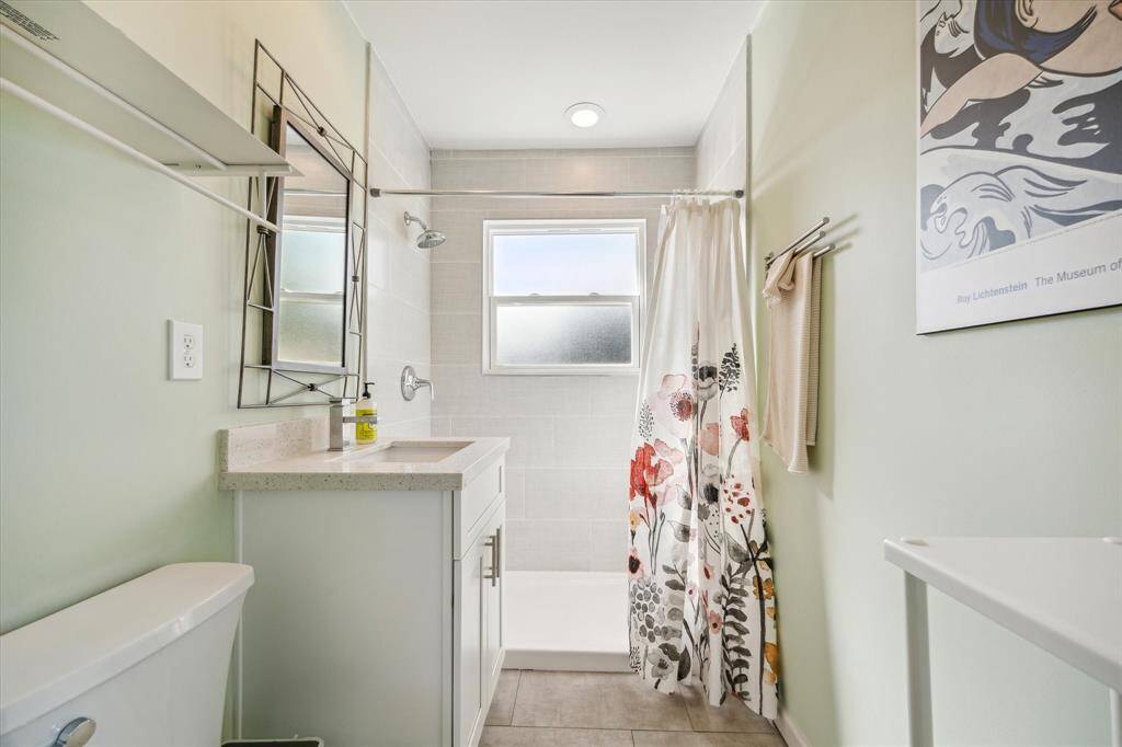 Accessible to guests off of the living room, full bath #3 is complete with Quartz counters topped by a porcelain vessel sink, tile flooring, and walk-in shower.