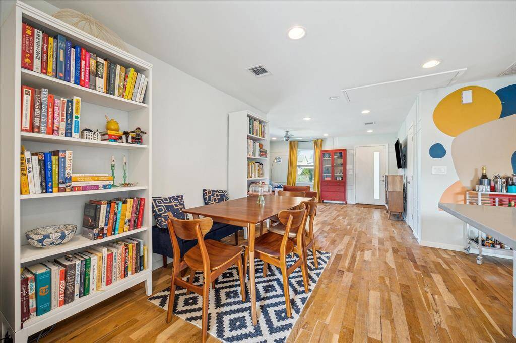 The open-concept kitchen and dining area showcases crisp white, soft-close cabinetry; a large center island, and hardwood flooring, blending functionality and style.