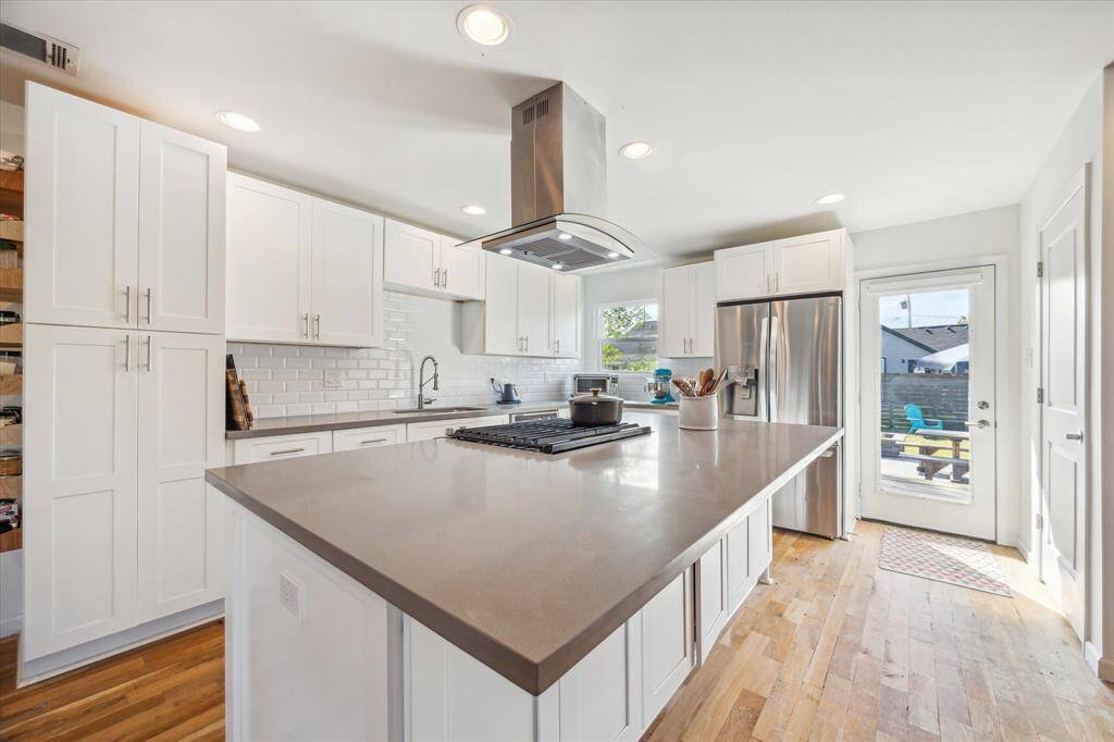 Beautiful Quartz countertops and a stainless steel appliance package complete the kitchen. Whirlpool appliances include dishwasher, under-counter microwave, 4-burner gas range with a vent hood above.
