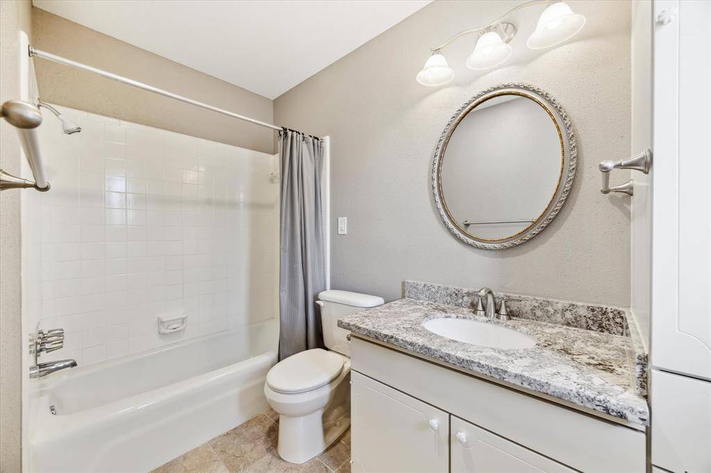 Ensuite bath with granite countertop and a shower/tub combo.