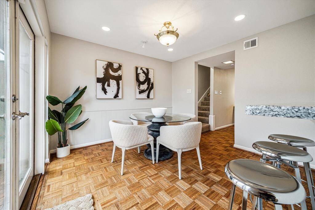The dining room features elegant wainscoting on one wall, seamlessly opens to the kitchen, and boasts French doors that lead to the back patio, creating an inviting space for both everyday living and entertaining.