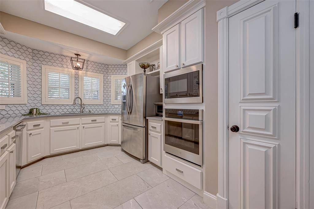 The kitchen boasts a built-in GE STAINLES STEEL MICROWAVE for quick heating and a single GE CONVECTION OVEN WITH BLUETOOTH CAPABILITY, providing advanced cooking options. This convection oven ensures even cooking, delivering delicious results for your culinary endeavors. Door leads to a convenient pantry, providing storage space for your groceries and kitchen essentials.