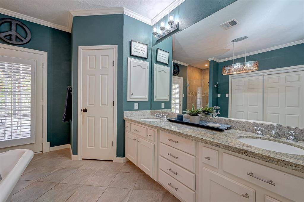 The owner's ensuite bathroom, measuring 12.7x11.2, boasts a spacious and well-appointed design. It features a GRANITE VANITY WITH DUAL SINKS, offering DRAWERS and plenty of storage space, complemented by a full wall mirror and a convenient medicine cabinet. UPDATED LIGHTING and crown molding add a touch of elegance to the space. The bathroom showcases porcelain tile throughout and includes a PRIVATE WATER CLOSET with the commode for added privacy.