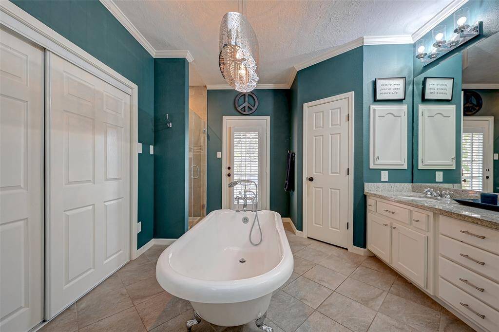 At the heart of the bathroom is a FREESTANDING CLAWFOOT TUB with a handheld sprayer, creating a luxurious space to relax and unwind. Through the door, you can enjoy a view of the gazebo and the inviting backyard, adding to the tranquil atmosphere of the owner's ensuite bathroom.