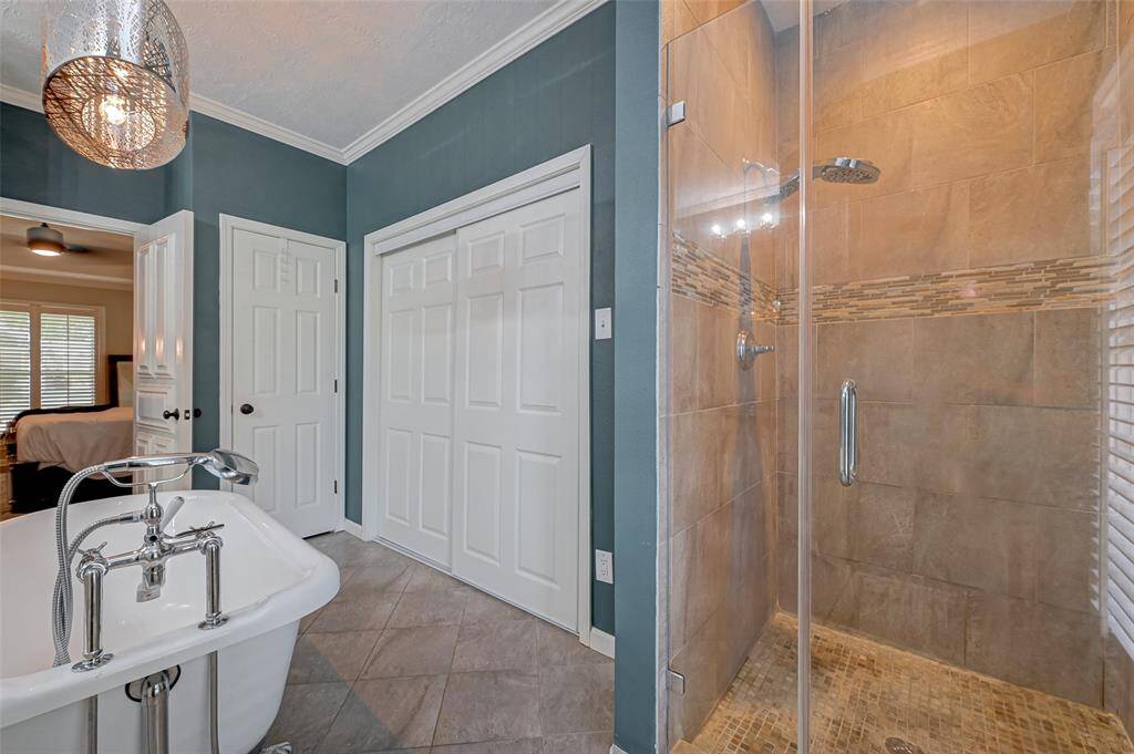 The bathroom includes a floor-to-ceiling walk-in shower with a glass door and decorative ribbon tile, providing a stylish and functional bathing space. It also houses 2 OF THE 4 CLOSETS for the owner's suite, ensuring ample storage. Additionally, there's an extra LINEN CLOSET for your convenience, adding to the bathroom's functionality.