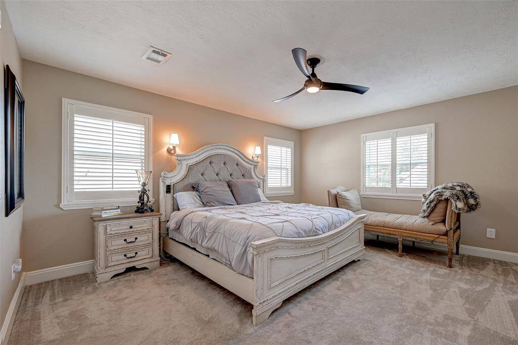 Bedroom #2, conveniently situated off the gameroom on the second floor, doubles as the SECOND PRIMARY SUITE. It offers a comfortable space measuring 15.4x14.2, complete with a ceiling fan for added comfort. Windows adorned with Plantation shutters provide a tasteful touch while allowing natural light to filter in.