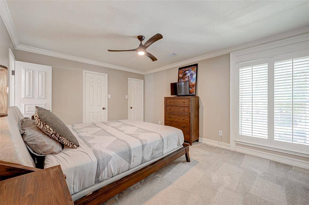 On the opposite side of the gameroom, you'll find Bedroom #3, measuring 15.8x12.4. It features windows with Plantation shutters that offers a lovely view of the front yard. This room includes crown molding and a ceiling fan for added comfort and 2 LIGHTED, WALK-IN CLOSETS, providing ample storage space for the occupants.
