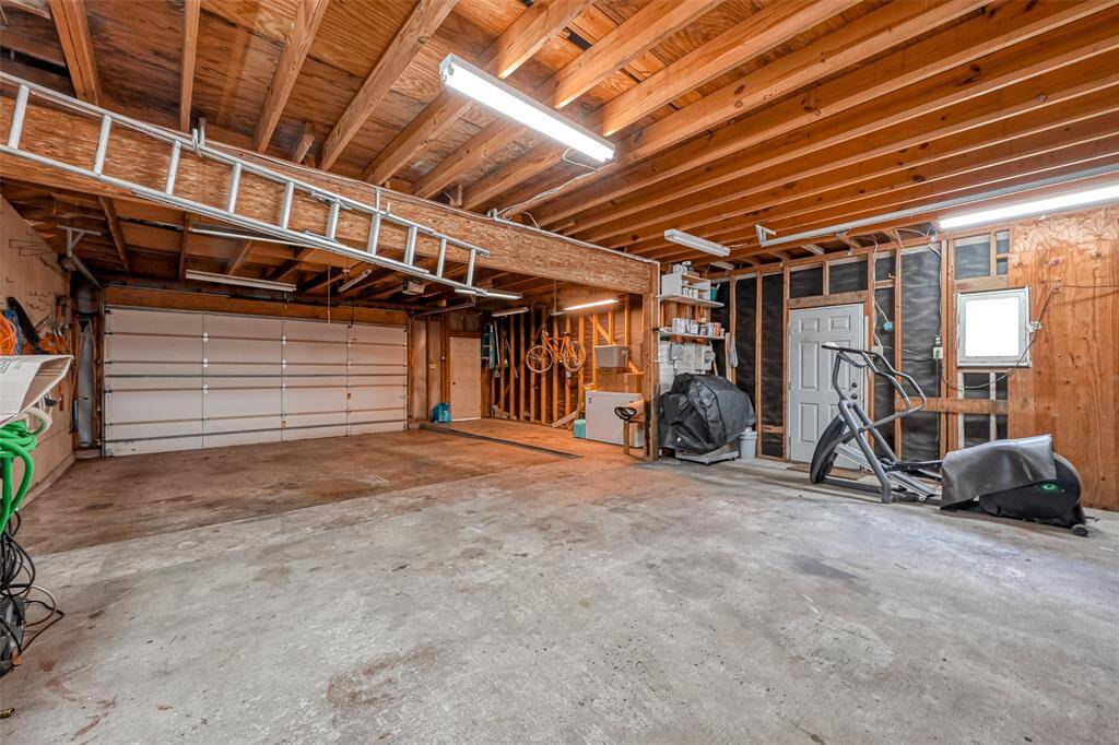 From the rear to the front garage door, abundant overhead lighting illuminates the space, perfect for any project. A 220 receptacle stands ready to power generator, air compressors, welders, or shop tools, adding to its versatility as a well-equipped workshop. Whether tinkering with cars or crafting, this space is tailor-made for your creative endeavors.