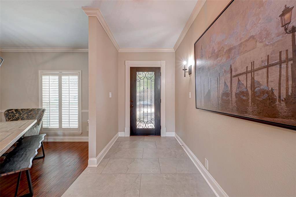 Indulge in contemporary elegance as you step through the lead glass door, inviting guests into an elevated foyer. The porcelain tile floor lends a sleek, modern touch, while crown molding embraces the space with timeless sophistication. Welcome to refined luxury from the moment you arrive.