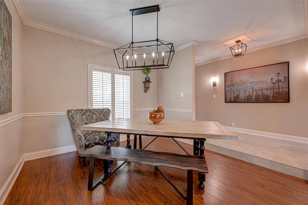 Descend from the foyer into the inviting formal dining room, graced with PLANK-STYLE WOOD LAMINATE FLOORING. Above, a modern wrought iron chandelier bestows a hint of contemporary elegance. Crown molding and chair-rail molding further enrich the space, crafting a sophisticated ambiance for memorable gatherings with family and friends. Welcome to refined dining in style.