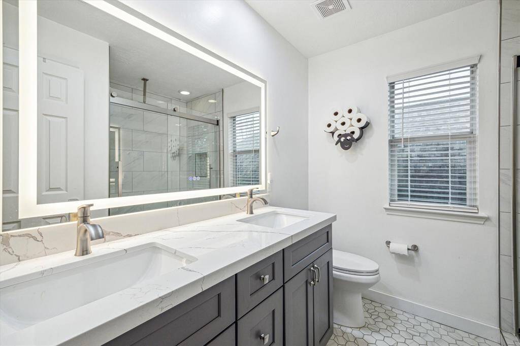 Upstairs full bath with a walk-in shower featuring a rainfall showerhead, seamless glass, LED mirror, and sophisticated marble tile, creating a luxurious, yet very modern feel.