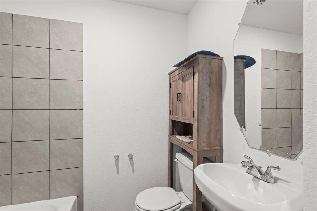 This bathroom features a classic shower/tub combo, a pedestal sink, and a toilet, providing a simple yet functional layout.