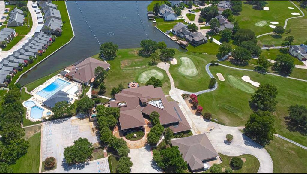 This aerial photo showcases a scenic view of the lake, featuring a golf course and a clubhouse with swimming pools. The community offers lush green spaces and waterfront living, ideal for those seeking a blend of leisure and luxury.
