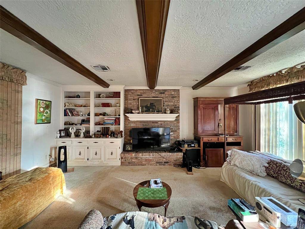 Spacious living room with a fireplace, built-in shelves and views of the backyard.