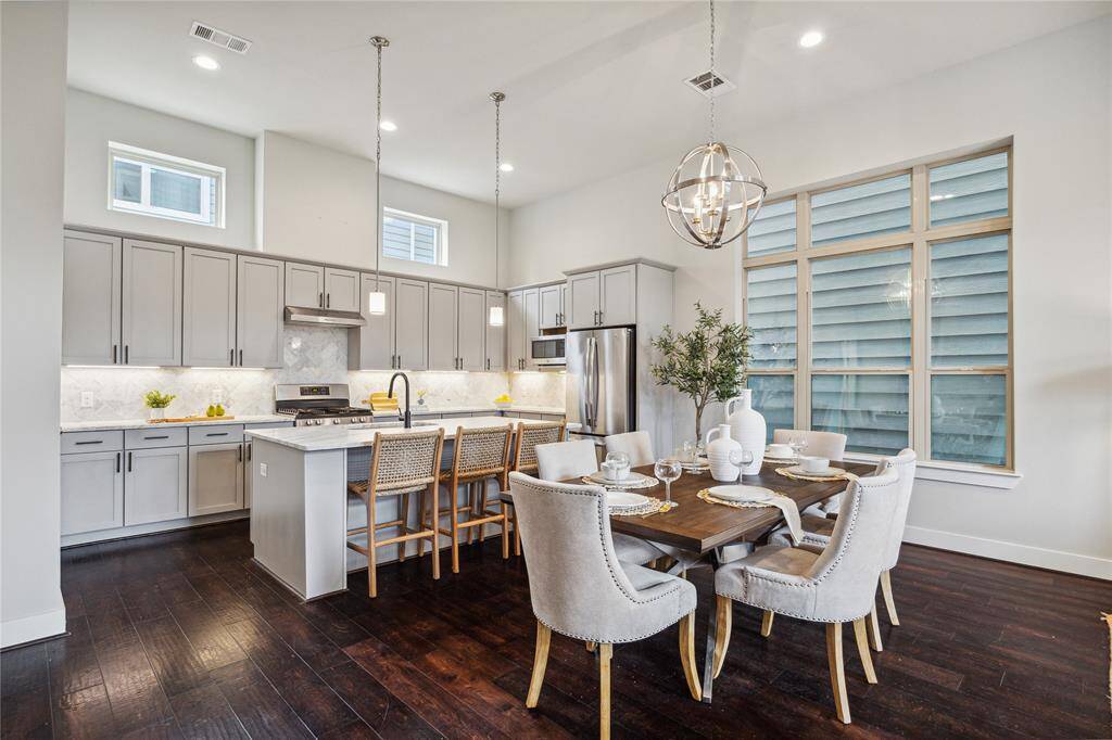 Modern light fixtures, rich wood flooring provide touches of elegance to this highly functional dining and kitchen space!*Home furnishings may differ*