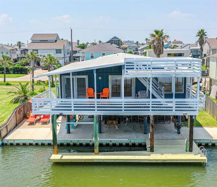 This waterfront home features a charming two-story design (second deck is a crow's nest) with a spacious wraparound deck offering scenic views. Elevated on pilings, it includes an outdoor seating area, direct water access, and a patio perfect for relaxation and entertaining.