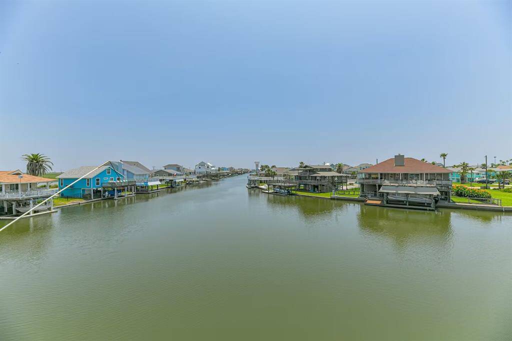 This photo shows a serene waterfront view with houses lining both sides of a calm canal. This home has a private dock extending into the water, offering a peaceful, picturesque setting perfect for water enthusiasts.