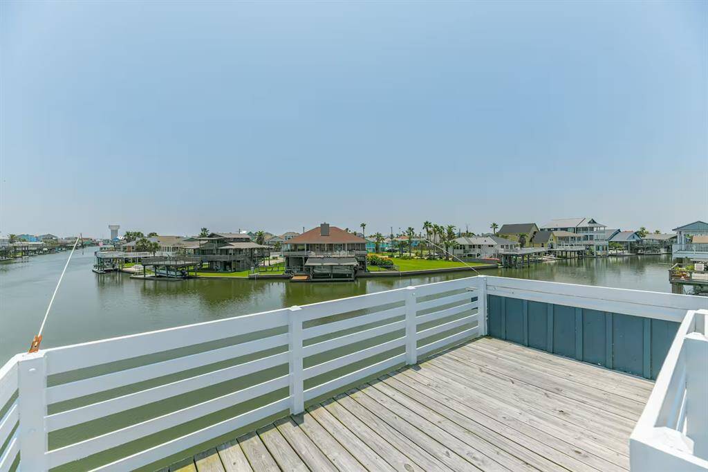 This photo showcases a waterfront property with a spacious deck overlooking a serene canal. The view includes neighboring homes, lush greenery, and water access, perfect for enjoying peaceful, scenic surroundings.  Sun deck or crow's nest.