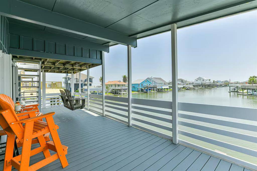 You will step outside to a very spacious covered deck with vibrant chairs and a porch swing, overlooking a serene waterfront.  Ideal for relaxation and enjoying picturesque views on this extra wide canal