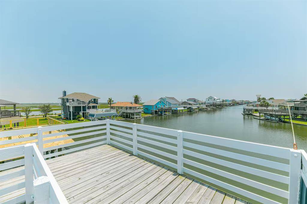 This photo showcases a waterfront view from a spacious deck, highlighting a serene canal lined with charming houses under a clear blue sky. Ideal for enjoying peaceful water views.  From the upper balcony.  Sun deck or crow's nest.