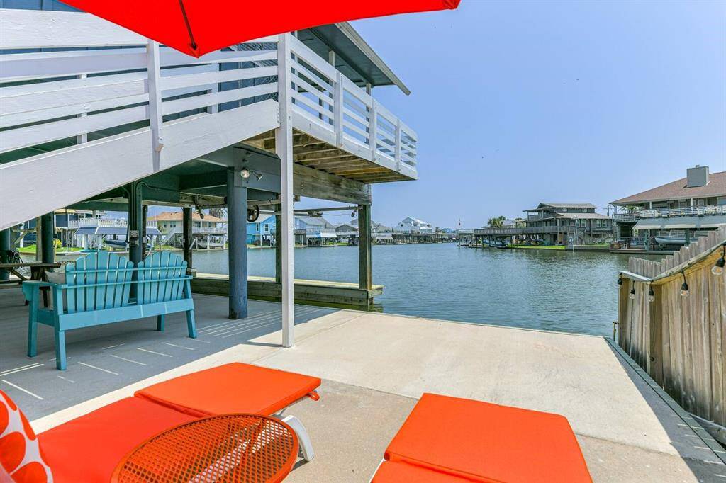 This waterfront property features a spacious patio with vibrant outdoor seating and a view of serene canal waters, perfect for relaxation and entertaining.