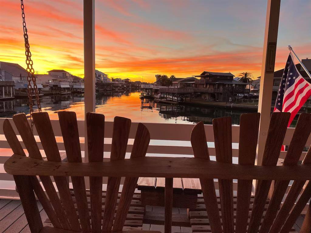 Immerse yourself in this peaceful and serene waterfront view from a cozy porch at sunset, featuring a wooden swing, a calm canal. Ideal for enjoying tranquil evenings by the water.