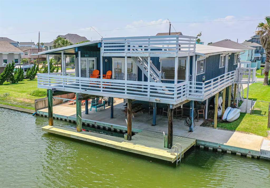 This waterfront home features an elevated structure with a spacious wraparound deck, perfect for enjoying canal views. It includes direct water access with a private dock, ideal for boating and outdoor activities. The property is surrounded by a lush green lawn, providing a serene coastal living experience. New boat dock, boat lift and fish cleaning table.