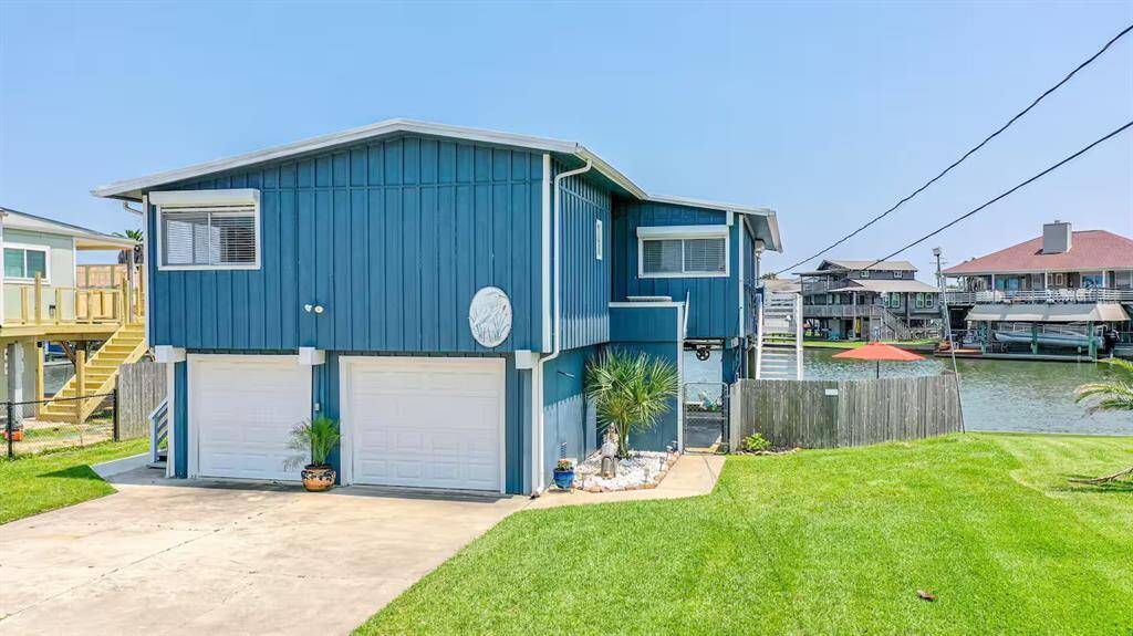 This waterfront home features a charming blue exterior with a two-car garage. It has a well-maintained lawn and direct canal access, perfect for boating enthusiasts. The setting offers a relaxed, coastal lifestyle.