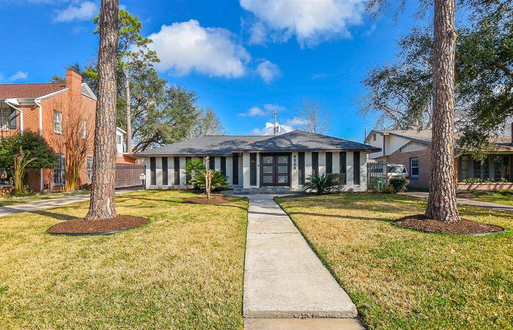 Discover this stylish single-story home featuring a modern facade with large windows and a welcoming double-door entrance. Enjoy the beautifully landscaped front lawn, accented by two mature trees and a paved walkway. Nestled in a charming neighborhood with character-rich brick homes nearby.