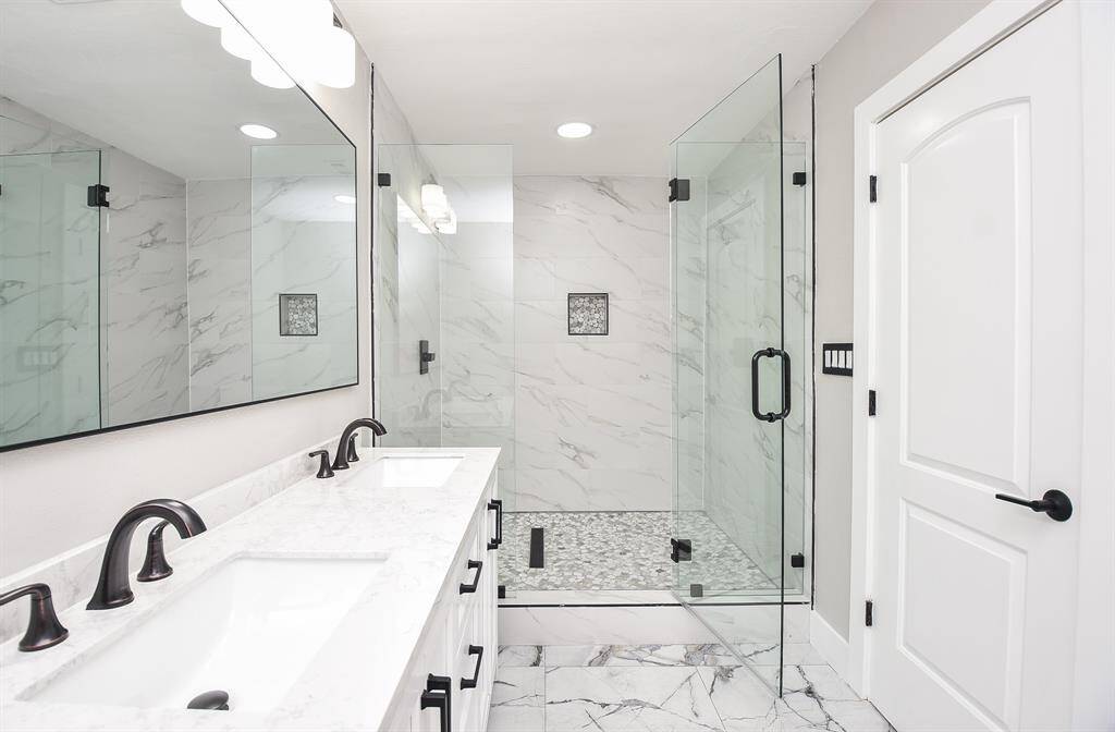 Experience luxury in the primary bath with a sleek rimless glass shower and elegant double vanity.