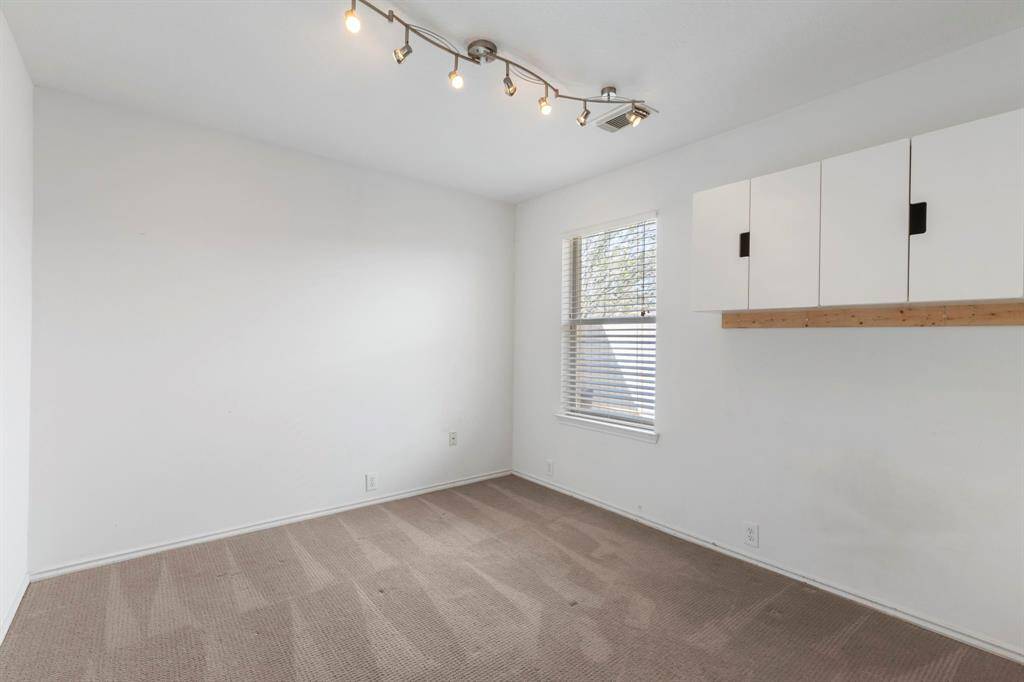 Cozy second bedroom with natural light, built-in storage, and modern track lighting.