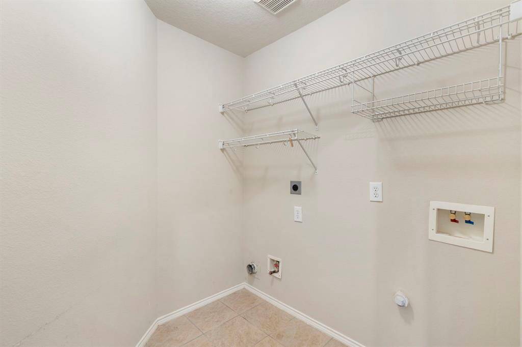 Efficient utility room with convenient shelving and essential hookups, perfect for laundry and storage needs.