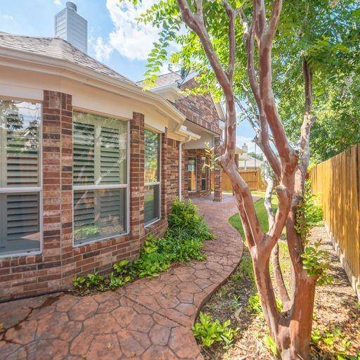 Stamped concrete room leads to front of home through iron gate