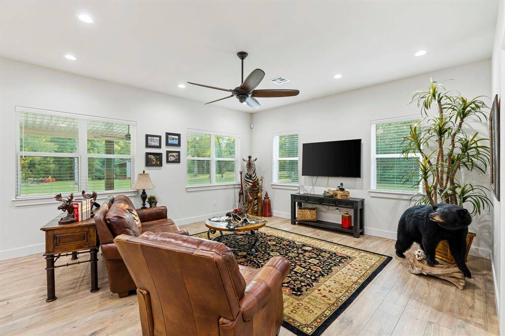 Living room features beautiful flooring, recessed lighting, ceiling fan, and large windows.
