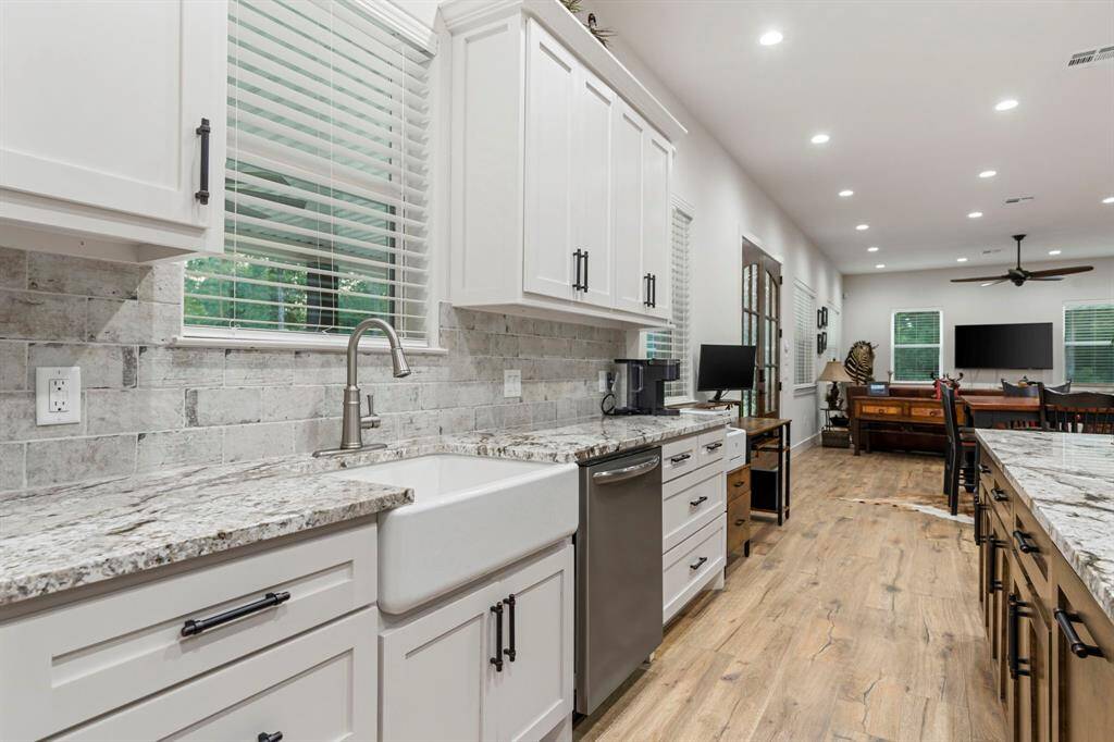 The kitchen also has a farmhouse sink and ceramic tile backsplash.
