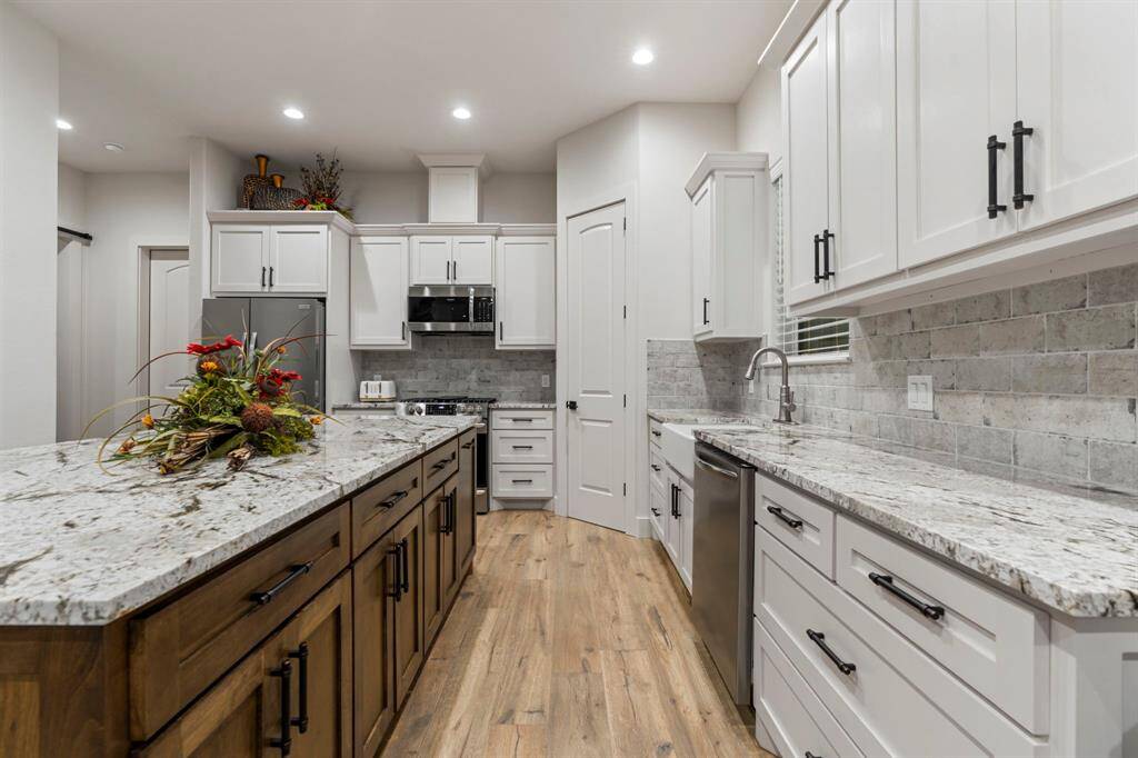 The kitchen also has a farmhouse sink and ceramic tile backsplash.