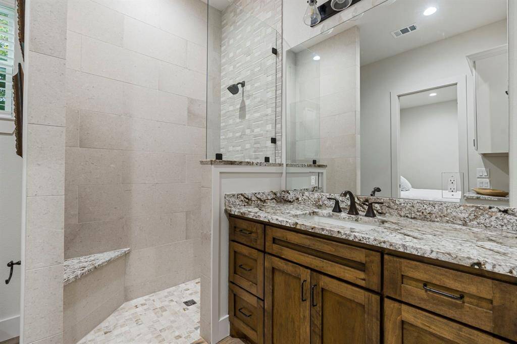 The primary bathroom has a walk-in shower with ceramic tile surround and granite countertops.