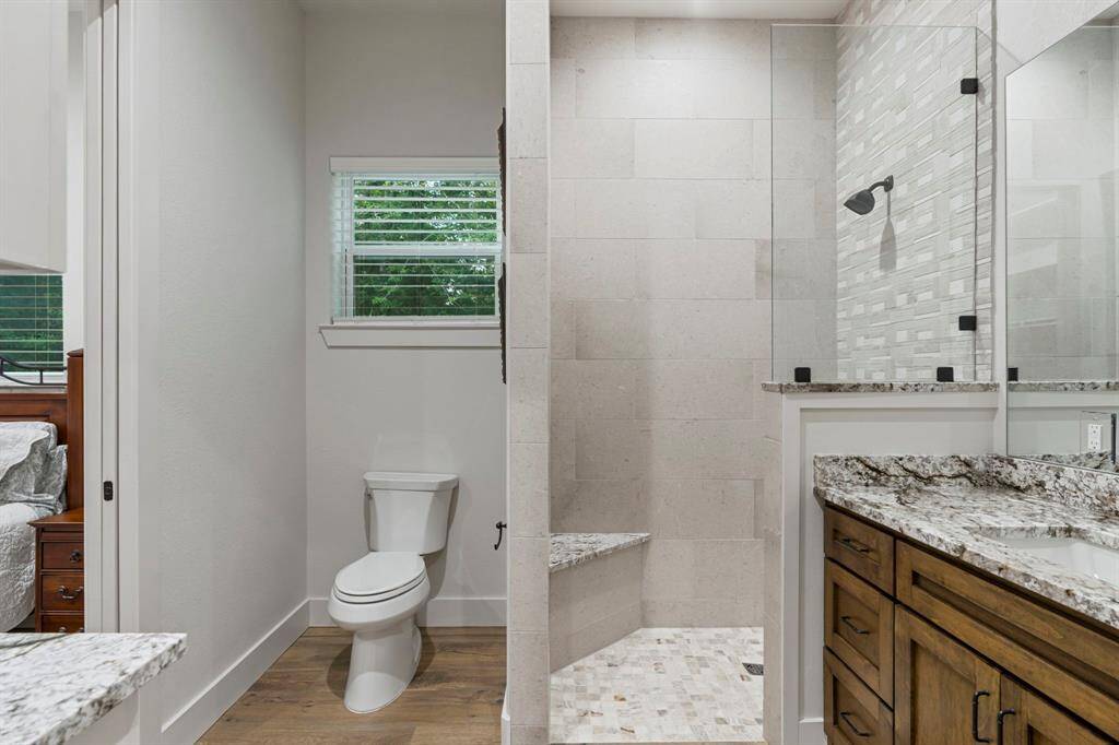 The primary bathroom has a walk-in shower with ceramic tile surround and granite countertops.