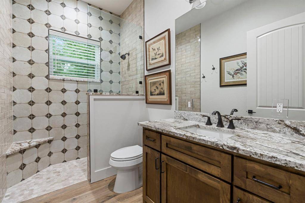 Secondary bathroom features a walk-in shower with ceramic tile sitting area and long vanity  with plenty of counter space.
